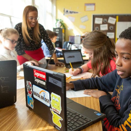 Photo of middle school students working on their laptops.