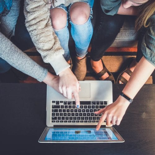 A group of people sharing ideas over a laptop screen.