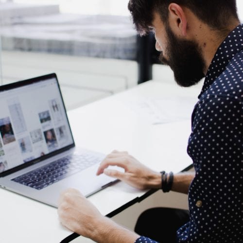 A man working on his laptop on a desk.